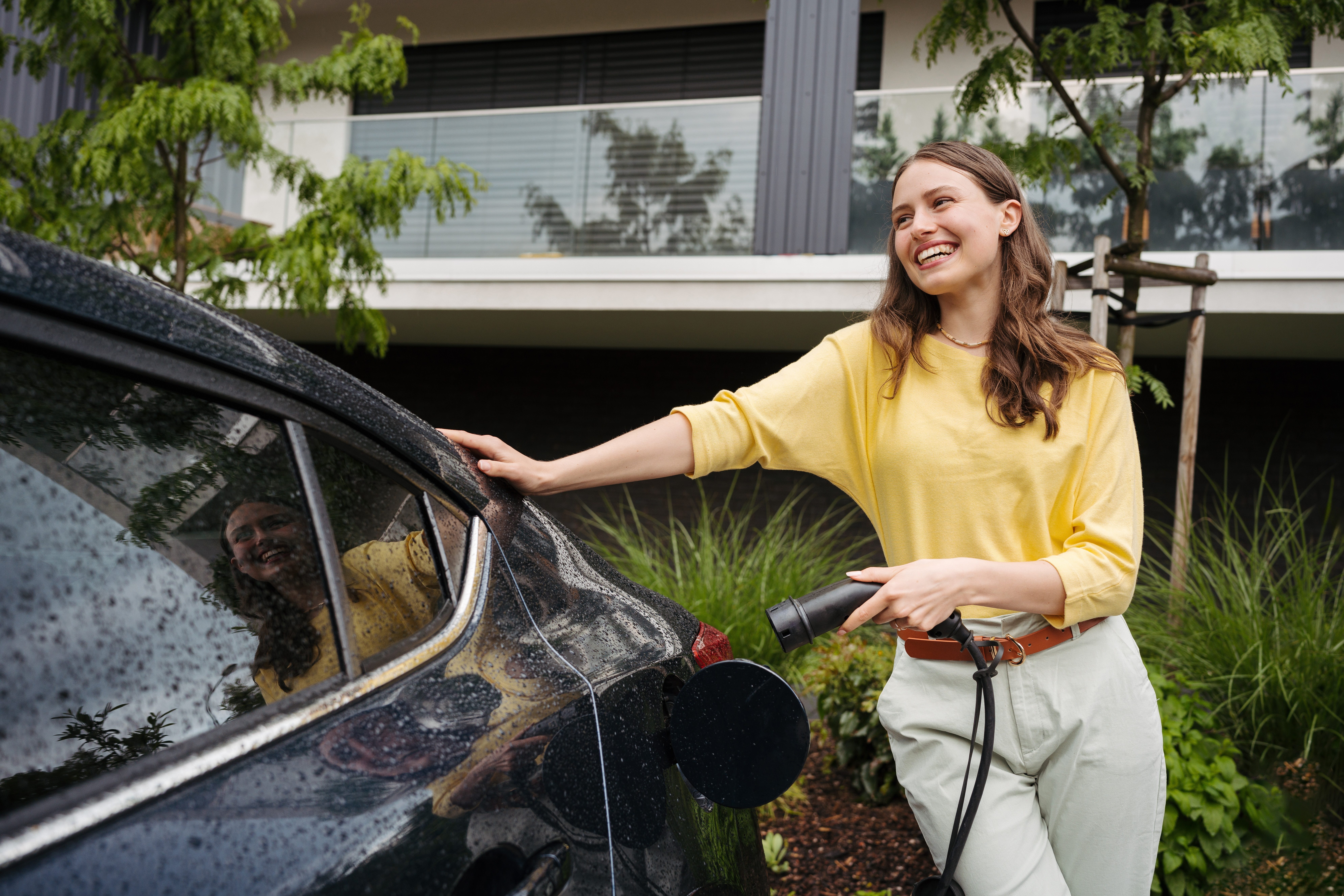 Young,Woman,Holding,Power,Supply,Cable,From,Her,Electric,Car,